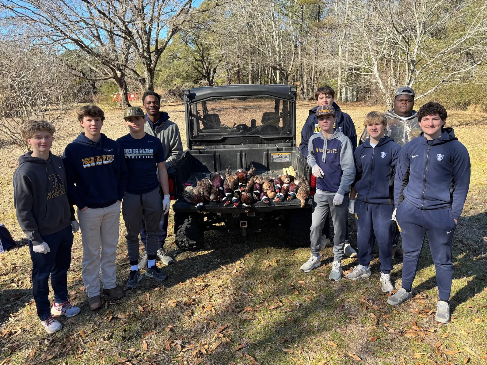 Tuscaloosa Academy student volunteers behind a utility vehicle lined with pheasants